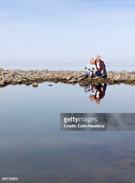 mature couple sitting on beach - porlock fotografías e imágenes de stock