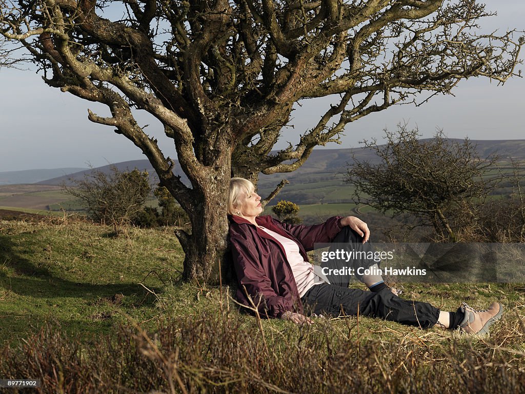 Mature woman leaning against tree