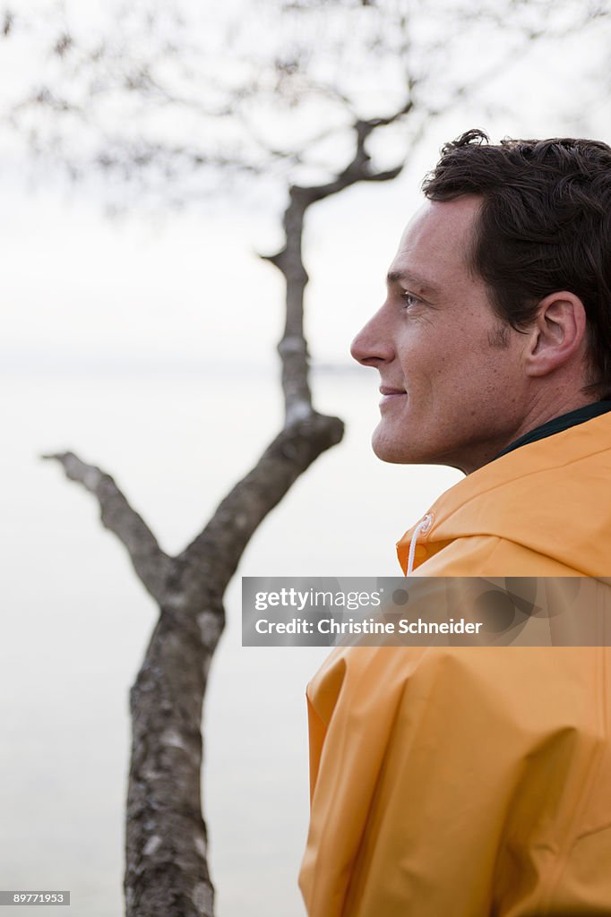 Man in raincoat looking on a lake