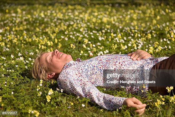 man lying in grass with spring flowers - müde frühling stock-fotos und bilder