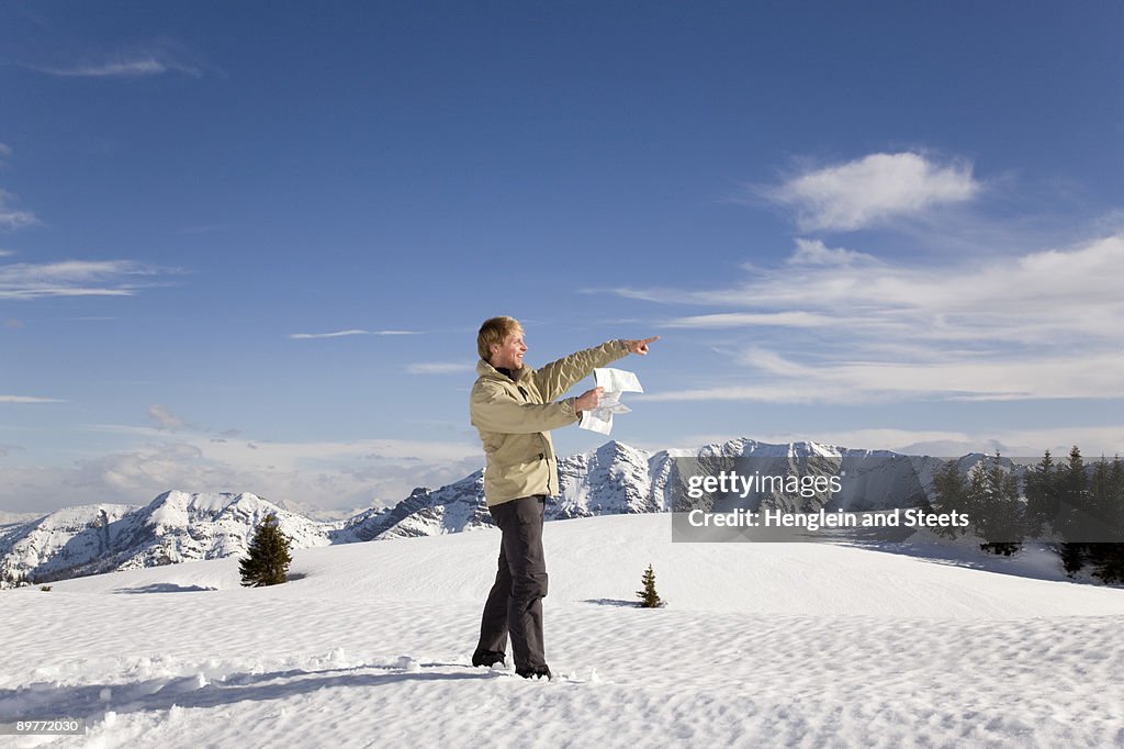 Man in mountains pointing with map