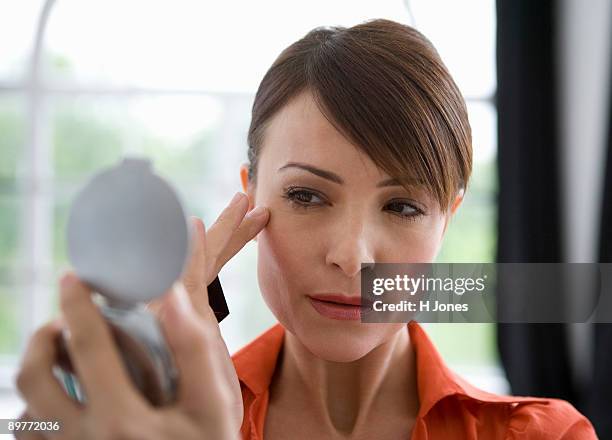 woman looking at skin in a mirror. - aging skin stock-fotos und bilder