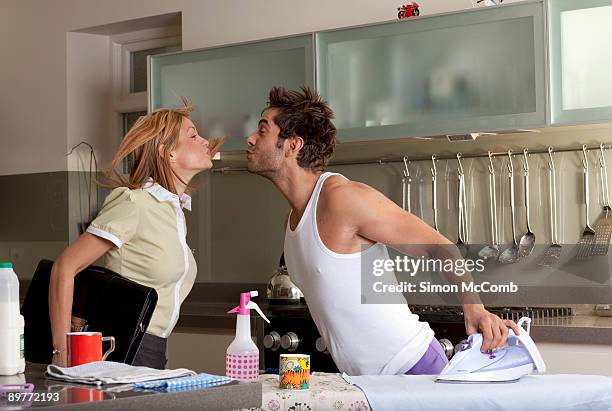 woman kissing partner in kitchen - rolwisseling stockfoto's en -beelden