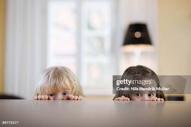 children looking over table edge - bambino curioso foto e immagini stock