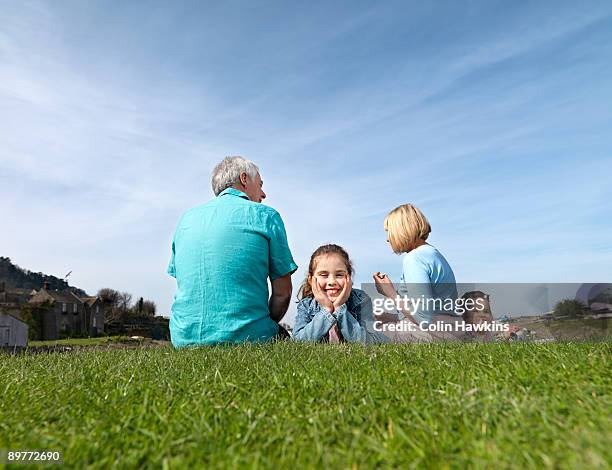 mature couple & children relax on grass - porlock stock pictures, royalty-free photos & images