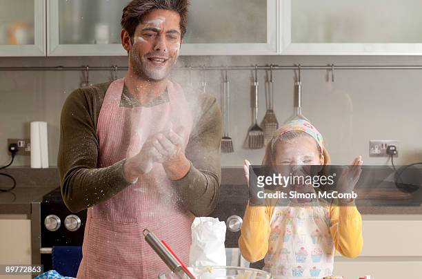 father and daughter cooking - messy kitchen stock-fotos und bilder