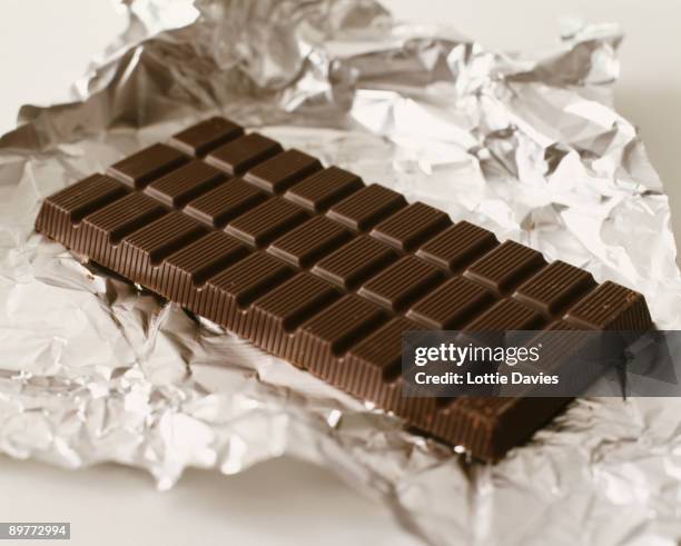 food - bar of dark chocolate on foil - riegel stock-fotos und bilder