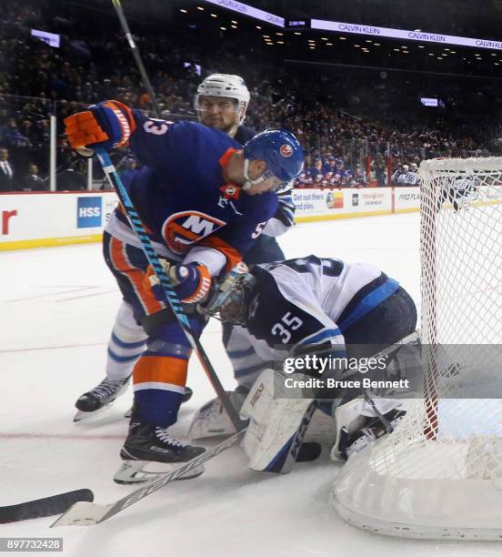 Casey Cizikas of the New York Islanders attempts to pry the puck loose from Steve Mason of the Winnipeg Jets during the second period at the Barclays...