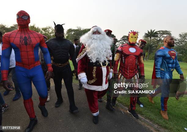 People dressed as Batman, Santa Claus, Iron Man and Superman walk at the presidential palace in Abidjan on December 23 during a Christmas event...