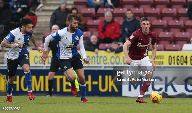 Chris Long of Northampton Town moves forward with the ball away from Derrick Williams and Elliott Ward of Blackburn Rovers during the Sky Bet League...