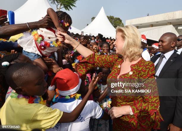 Ivory Coast's First Lady Dominique Ouattara shakes hands with children at the presidential palace in Abidjan on December 23 during a Christmas event...