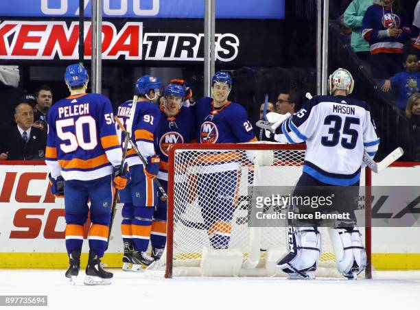 Anthony Beauvillier of the New York Islanders scores at 15:01 of the third period against Steve Mason of the Winnipeg Jets and is joined by Adam...