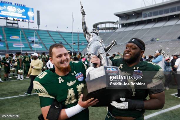 Spencer Adkinson and Jeremi Hall of the South Florida Bulls carry the championship trophy following the Birmingham Bowl against the Texas Tech Red...