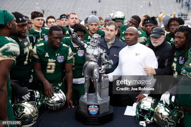 Head coach Charlie Strong of the South Florida Bulls gathers his team around the championship trophy following the Birmingham Bowl against the Texas...