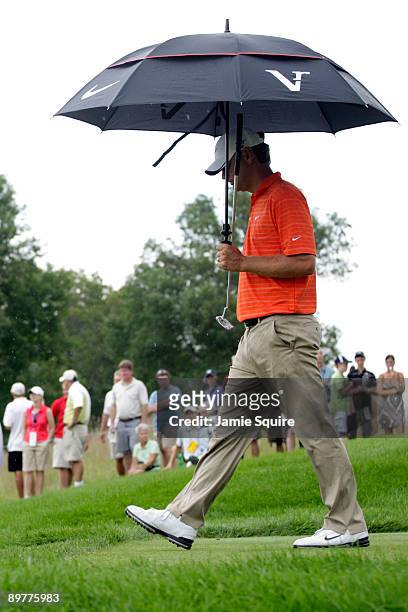 Lucas Glover waits under an umbrella on the seventh hole during the first round of the 91st PGA Championship at Hazeltine National Golf Club on...