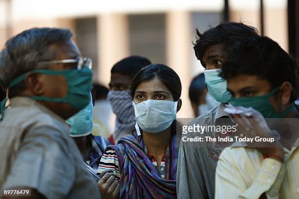 People wearing surgical masks wait for swine flu screening in New Delhi on Saturday, August 8, 2009.