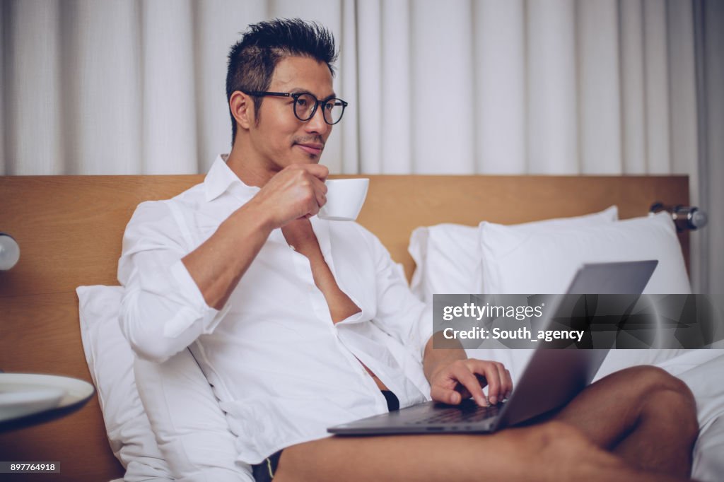 Attractive man using laptop in the bed