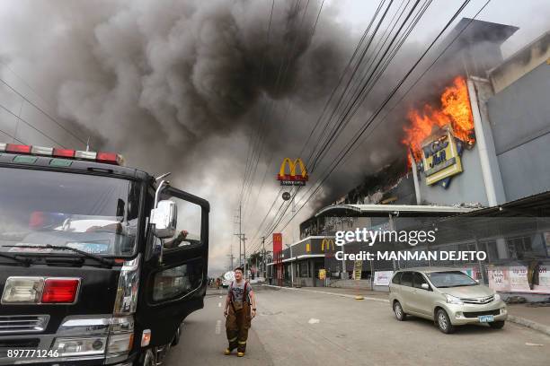 This photo taken on December 23, 2017 shows a firefighter standing in front of a burning shopping mall in Davao City on the southern Philippine...