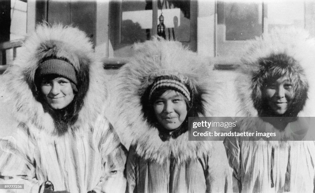 Three Eskimo girls wearing their chubby parkas: Wolfskin around their faces should protect them from wind, snow and cold. Photograph. Around 1935.