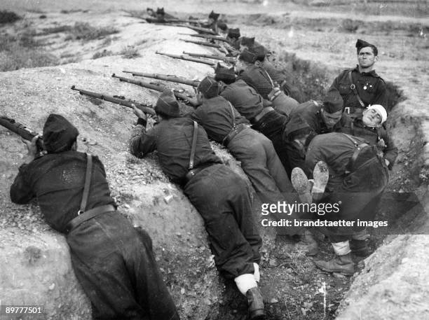 The Guadarrama trenches of the Nationalists in the battles of Madrid. The soldiers with their guns are in positon whilst a wounded is carried away....