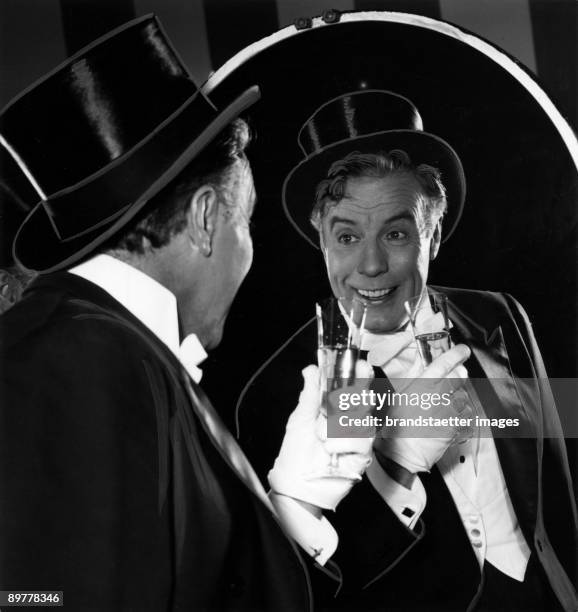 Actor Johannes Heesters in front of a mirror as his most favourite character, ther Count Danilo. Photograph. Around 1955.