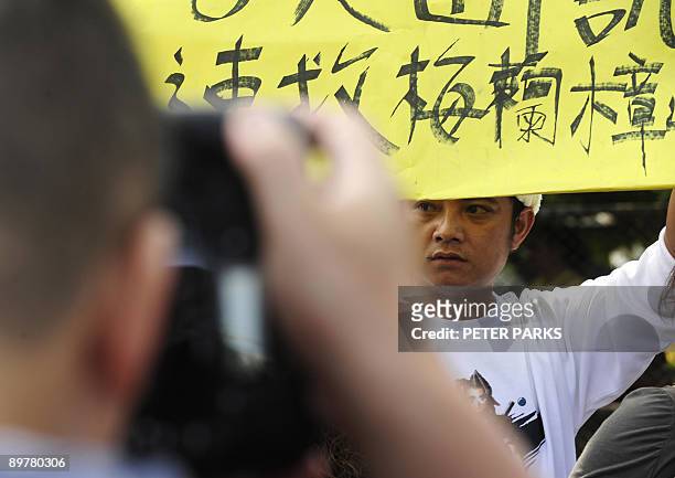 Man displays a poster demanding rescue teams take immediate action to evacuate his relatives from the mountainous Meilanchang area, at Chishan rescue...