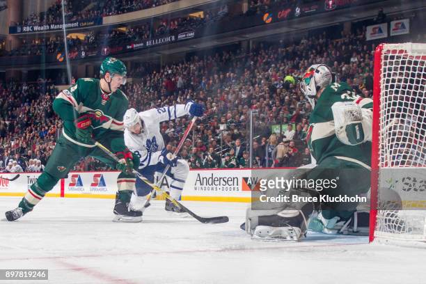 Mike Reilly and goalie Alex Stalock of the Minnesota Wild defend their goal against Connor Brown of the Toronto Maple Leafs during the game at the...