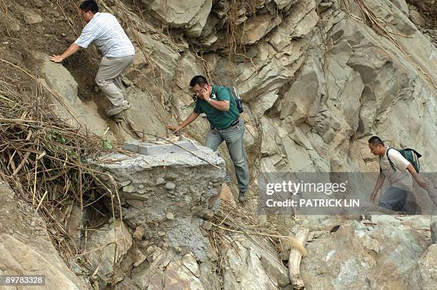 Rescurers climb on the rocks along the river at the village of Meishan in Chiayi county, southern Taiwan, on August 14, 2009. Rescuers in Taiwan on...