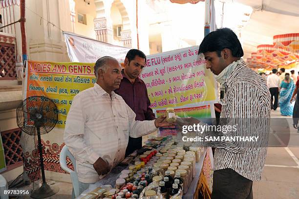 Indian ayurvedic doctor Amratlal Soni and son Harshad interact with a prospective customer as they sell ayurvedic medicines from a stall at The...