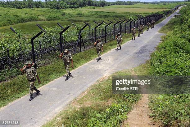 Indian Border Security Force personnel patrol alongside a barbed wire fence which marks the border with Bangladesh at Patriduwar, some 75kms south of...