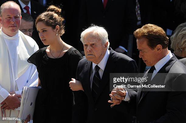 Husband Sargent Shriver is helped by California Gov. Arnold Schwarzenegger out of St. Xavier Church after Eunice Kennedy Shriver's funeral August 14,...