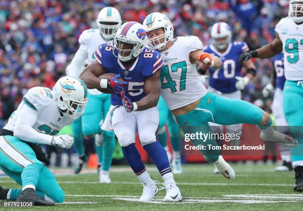 Charles Clay of the Buffalo Bills runs with the ball as he is tackled by Kiko Alonso of the Miami Dolphins and T.J. McDonald during NFL game action...