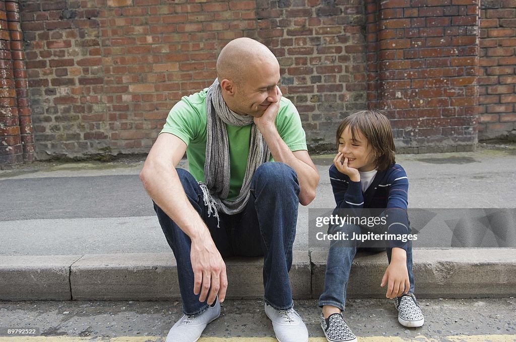 Father and son sitting on curb