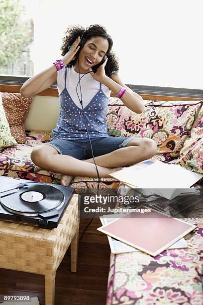 teenage girl singing and listening to headphones - a woman modelling a trouser suit blends in with a matching background of floral print cushions stockfoto's en -beelden