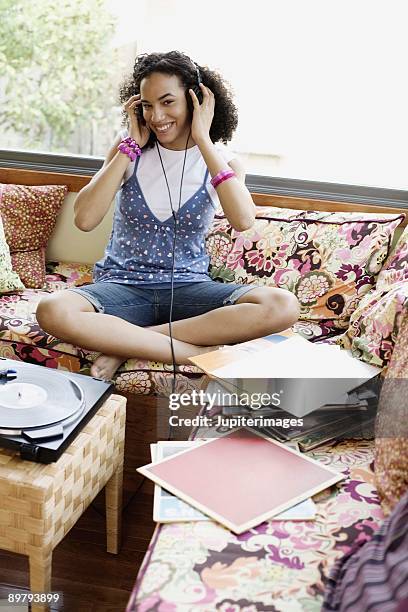 teenage girl listening to headphones - a woman modelling a trouser suit blends in with a matching background of floral print cushions stockfoto's en -beelden