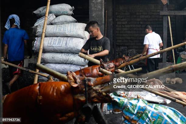 Workers prepare roasted pigs for packaging on Christmas Eve in Manila on December 24, 2017. Locally known as 'lechon' or roasted suckling pig, the...