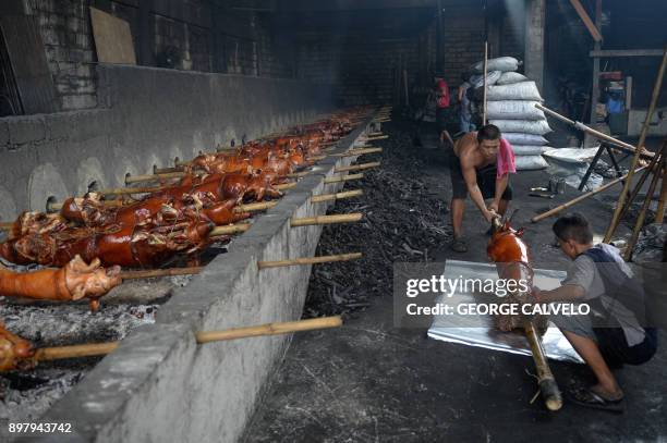 Workers prepare to wrap a roasted pig fresh from a grill on Christmas Eve in Manila on December 24, 2017. Locally known as 'lechon' or roasted...