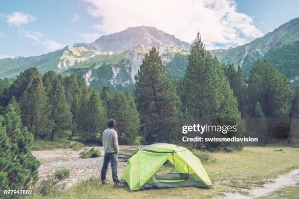 caucasian male relaxing beside tent at sunset, switzerland - bivouac stock pictures, royalty-free photos & images