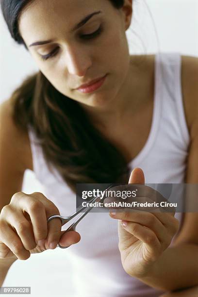 young woman trimming finger nails with nail scissors, close-up - nail scissors - fotografias e filmes do acervo