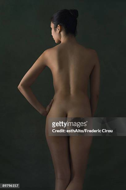 nude woman standing with hand on hip, rear view - female derriere stockfoto's en -beelden