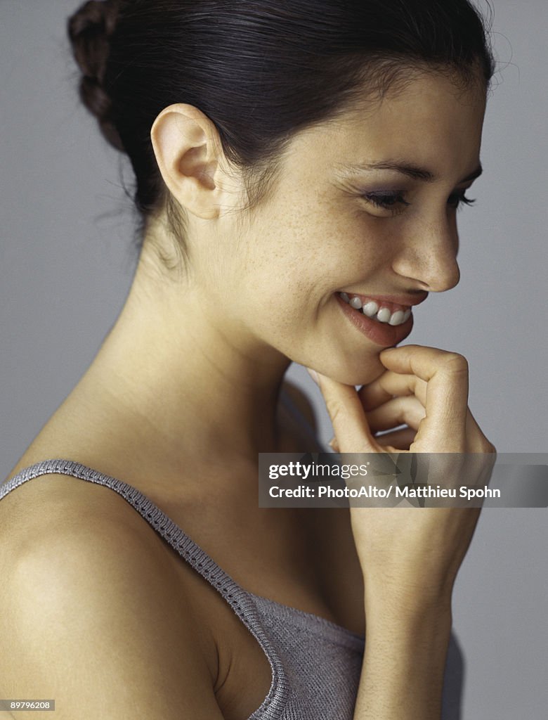 Young woman holding chin, smiling, profile