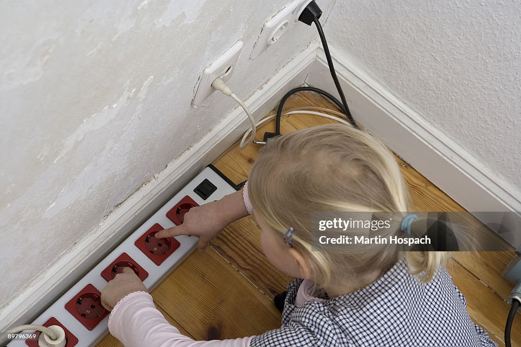 A young girl touching an electric outlet