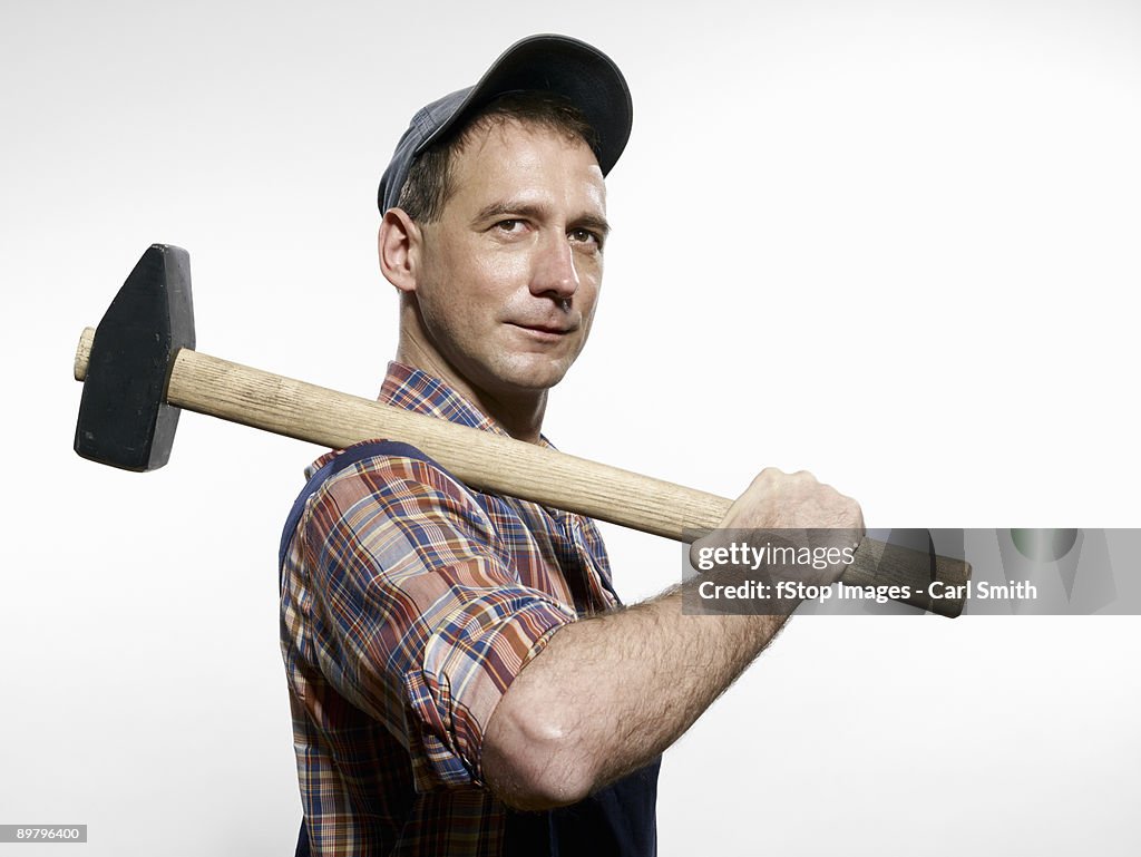 A man holding a sledgehammer over his shoulder