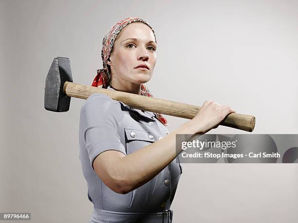 a woman holding a sledgehammer over her shoulder - comunismo foto e immagini stock