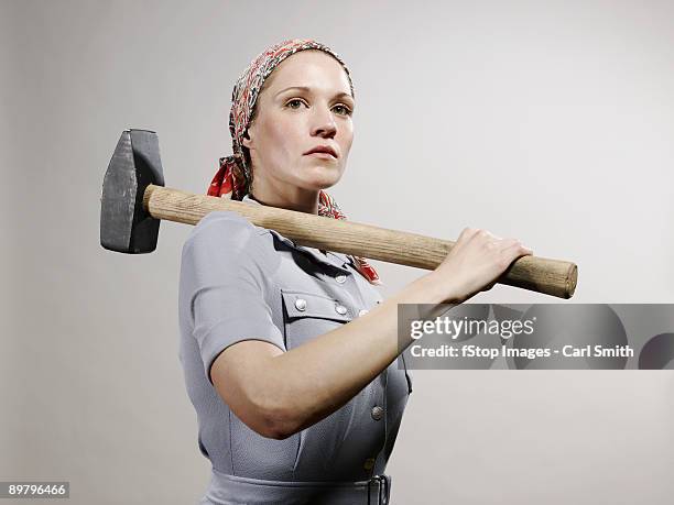 a woman holding a sledgehammer over her shoulder - sledgehammer stockfoto's en -beelden
