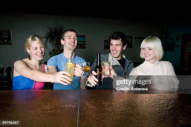 Four Friends Toasting Drinks At A Bar High-Res Stock Photo
