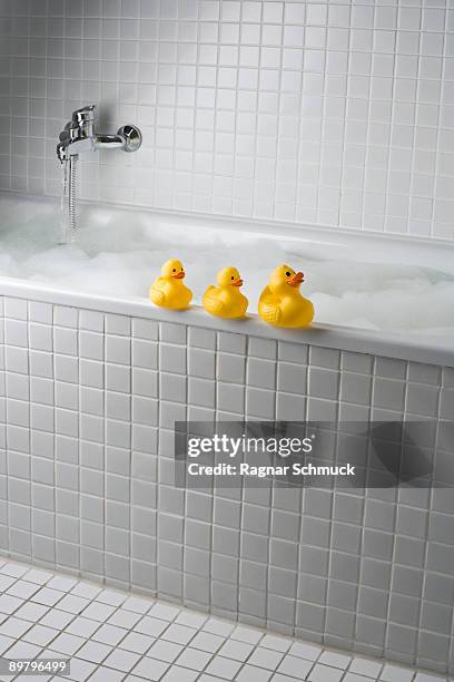 a bubble bath with rubber ducks on side of tub - rubber ducks in a row stock pictures, royalty-free photos & images