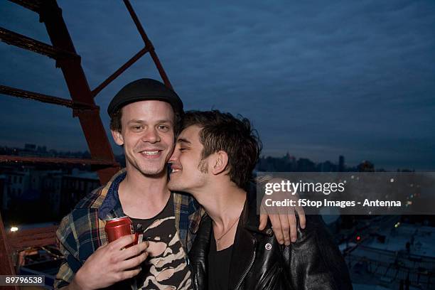 a young couple embracing on a fire escape - gay leather stock pictures, royalty-free photos & images