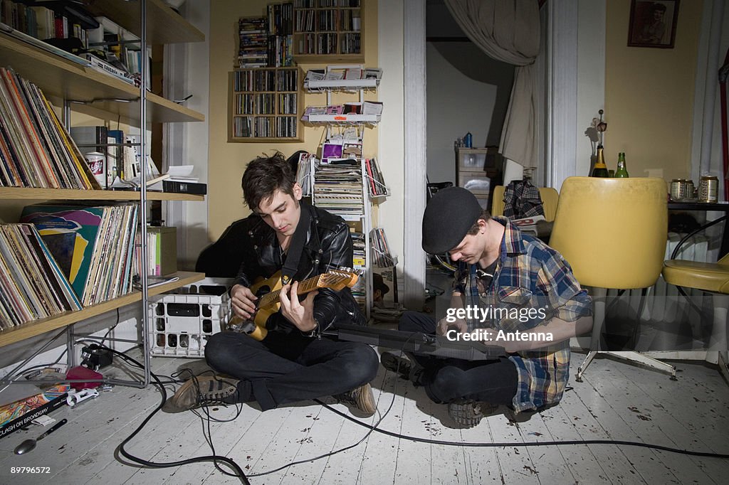 Two young men playing instruments in their living room