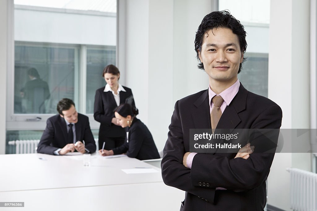 Portrait of a businessman in a board room with out of focus business people in background